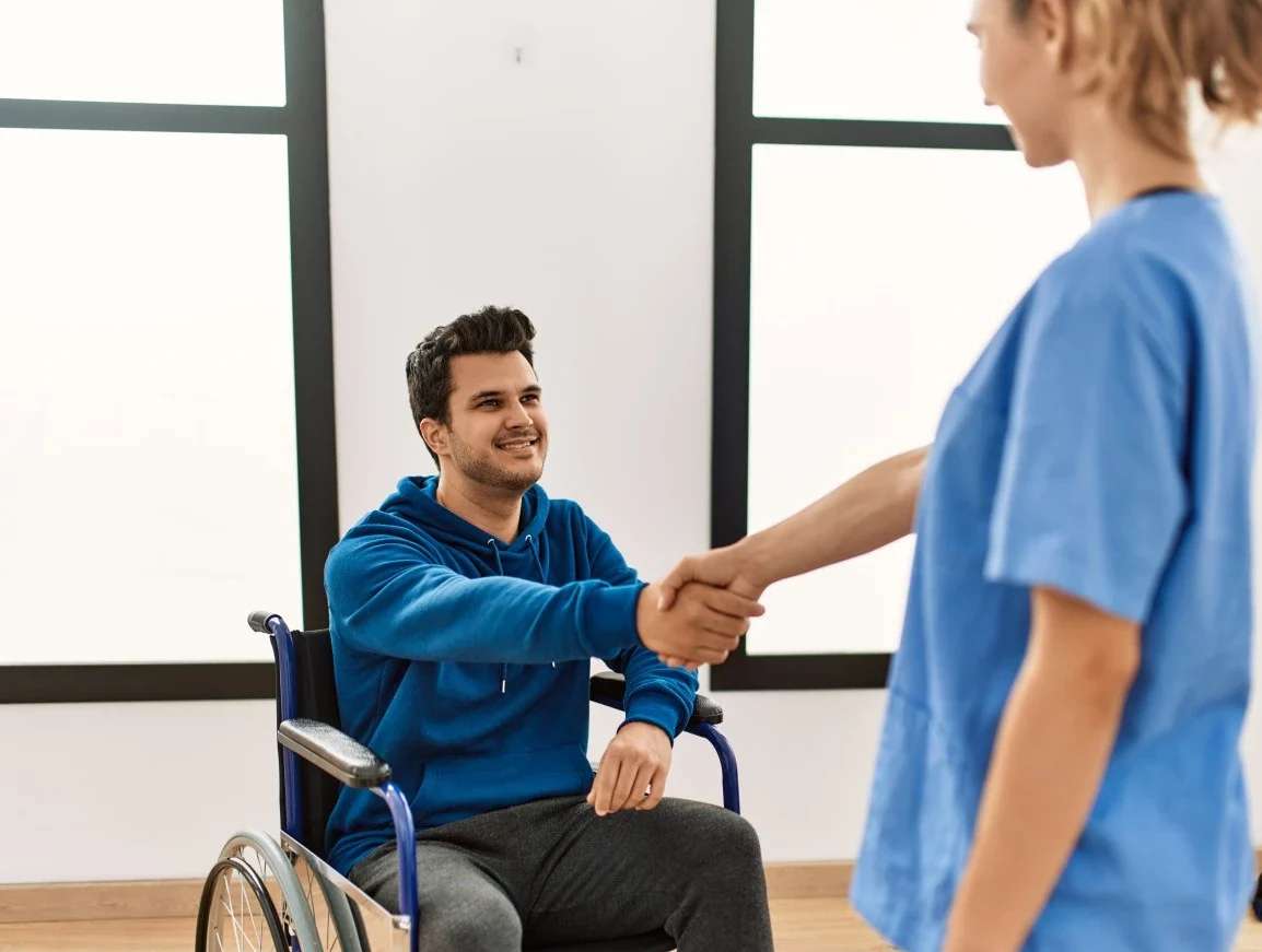 Nurse shaking hand of disabled man in wheelchair