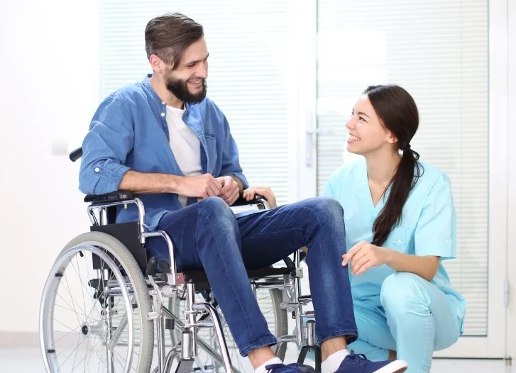 Disabled man in wheelchair smiling with nurse