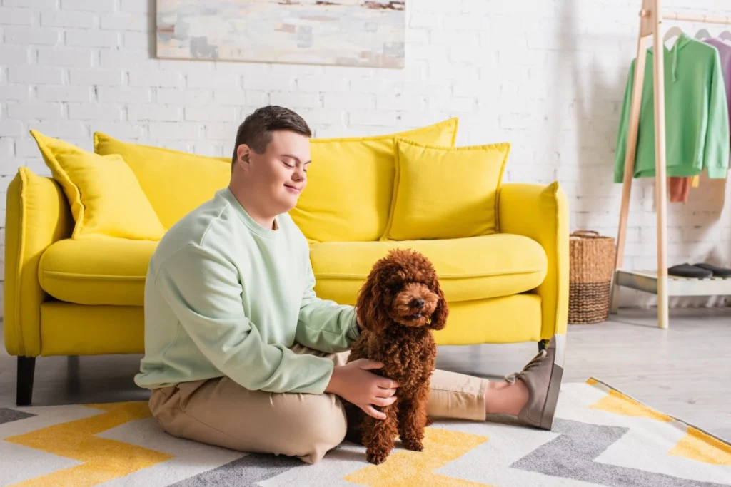 Disabled boy with down syndrome sitting on living room floor with dog