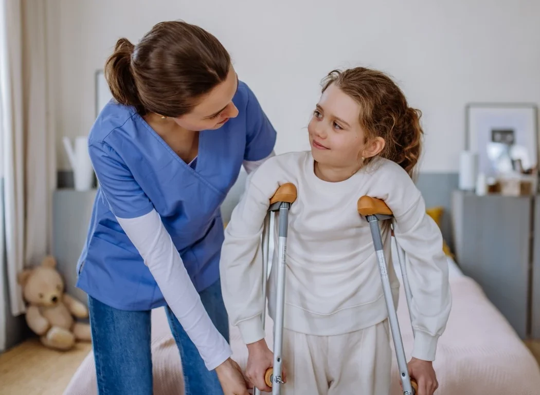 Nurse with young disabled girl with crutches